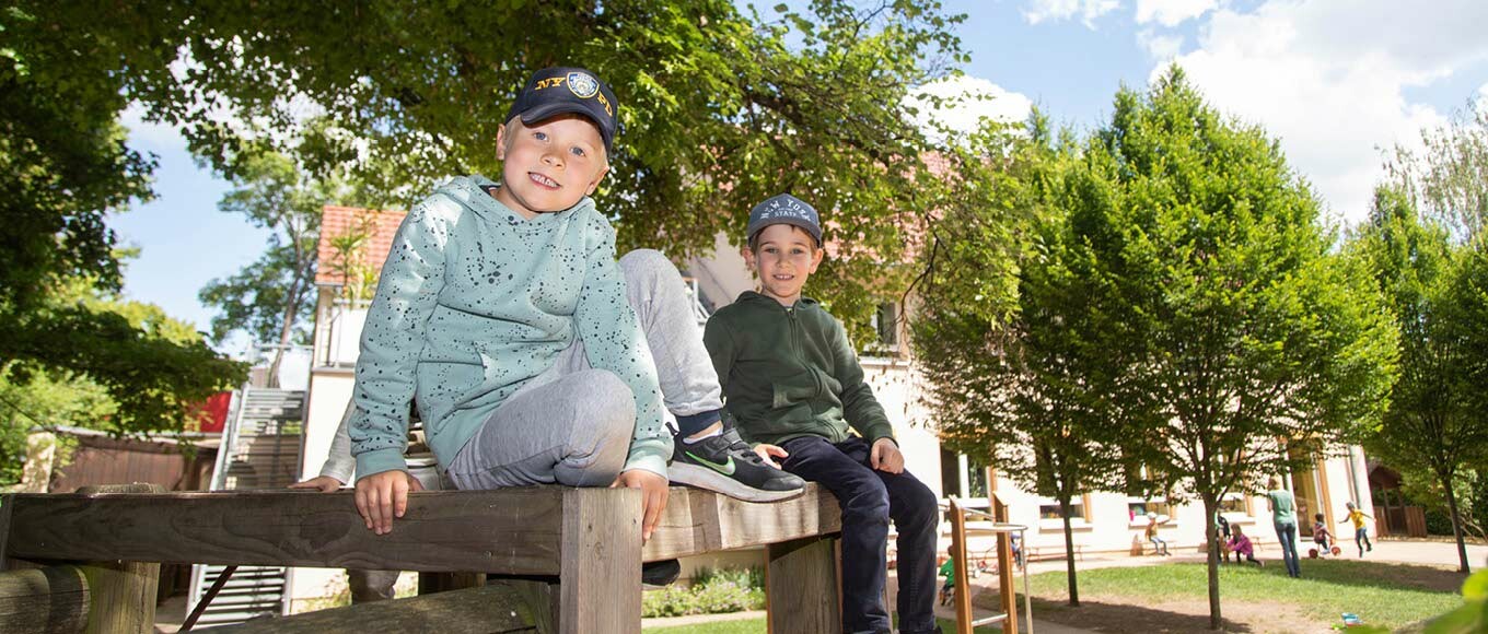 Zwei Jungs sitzen auf einem Holzzaun im Grünen