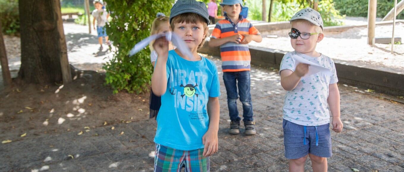 Jungs und Mädchen spielen mit Papierflugzeugen